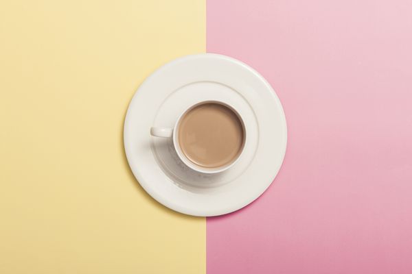 یک فنجان قهوه شیر بر روی کاغذ رنگی صورتی زرد