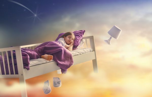 رویاهای بچه ها دختر بچه ناز در آسمان تختخوابش از طریق ستاره پرواز می کند