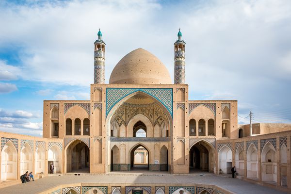 نمایی متقارن از اثر موزائیک و معماری رنگی ماسه سنگ اسلامی مسجد آقا بزرگ در شهر کویری کاشان ایران در ساعت طلوع آفتاب