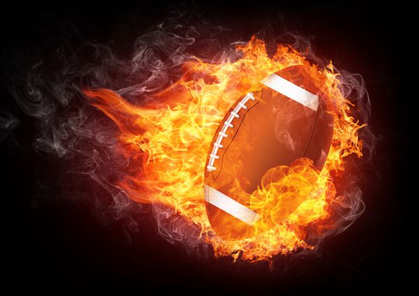 سوزاندن توپ فوتبال که در شعله آتش جدا شده بر روی پس زمینه سیاه پوشیده شده است