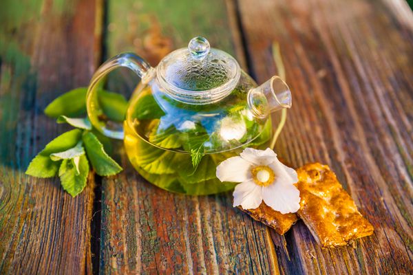 قابلمه چای گیاهی روی یک میز چوبی