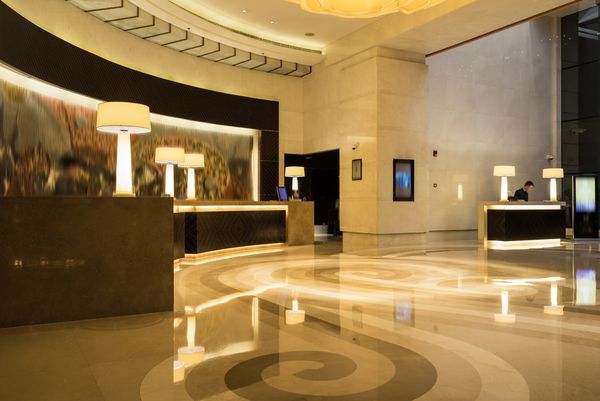 فضای داخلی لابی هتل با میز پذیرش کف مرمر و لامپ کریستالی