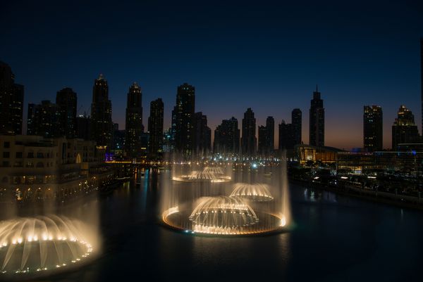 DUBAI امارات 31 ژانویه 2017 چشمه معروف موسیقی در دبی با آسمان خراش ها در پس زمینه در یک شب زیبا در تابستان