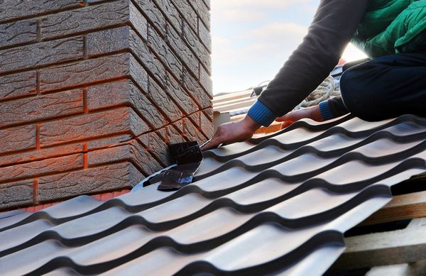 کارگر سازنده Roofer ورق فلزی را به دودکش وصل می کند ساخت سقف ناتمام