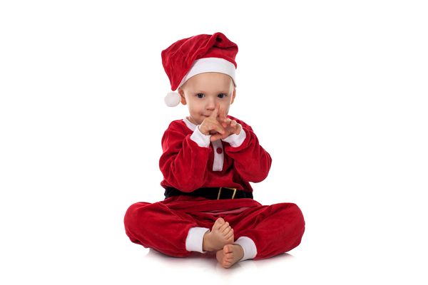 کودک کوچک در کت و شلوار سانتا می خندد و لبخند می زند کودک در لباس کریسمس قرمز جدا شده در پس زمینه سفید