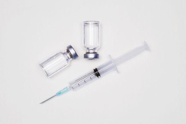 بطری دارو برای تزریق ویال های شیشه ای پزشکی و سرنگ برای واکسیناسیون داروی مایع یا واکسن برای درمان آنفولانزا در آزمایشگاه بیمارستان یا داروخانه مفهوم جدا شده بر روی زمینه سفید