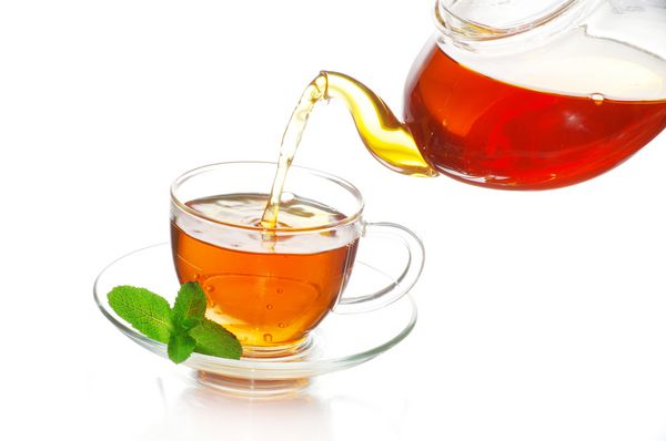 چای که داخل لیوان چای شیشه ای ریخته می شود