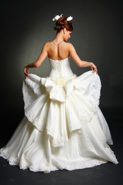 مدل لباس پوشیدن لباس عروسی در پس زمینه استودیوی سیاه
