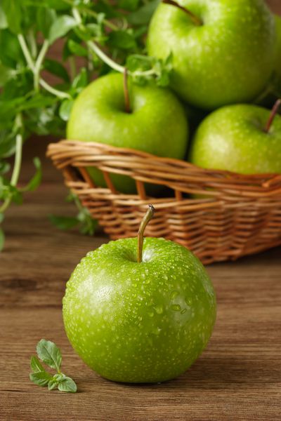 سیب سبز با قطره آب و نعناع تازه باغ روی یک میز چوبی