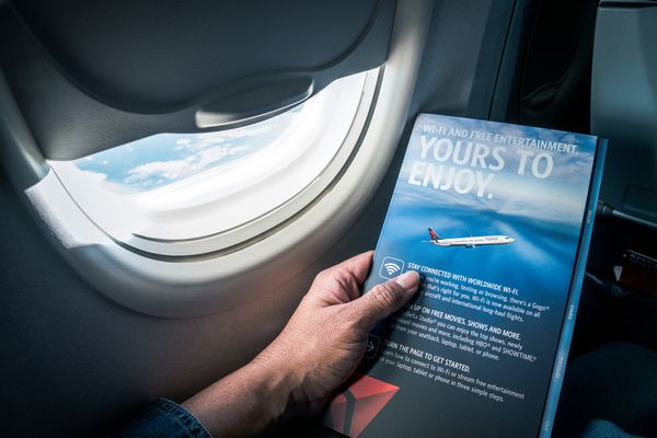 لس آنجلس ایالات متحده 12 2017 یک مرد آسیایی دستورالعمل های ایمنی پرواز هواپیمایی Delta Airlines و سرویس های موجود در پرواز را از روی صفحه کارت خواند