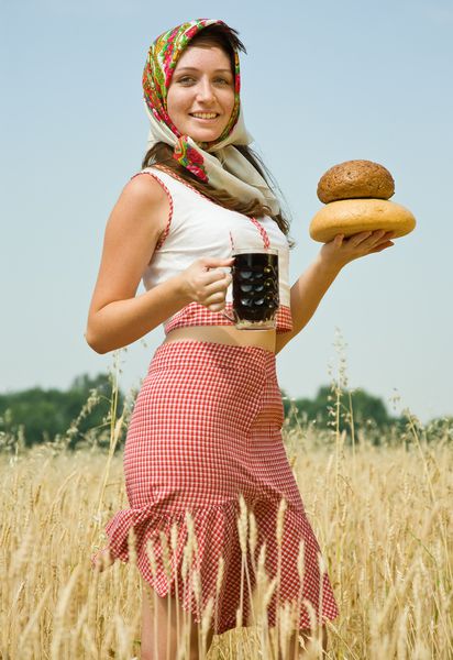 دختر با لباس های سنتی با نان و کواس در مزرعه گندم