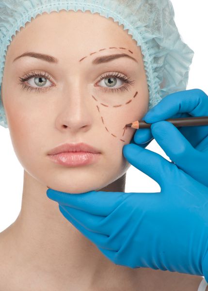 زن جوان زیبا با خطوط سوراخ روی صورت خود قبل از عمل جراحی پلاستیک زیبایی زن که چهره زن را لمس می کند
