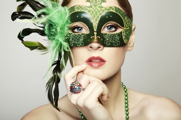 زن جوان زیبا در یک ماسک ونیز سبز مرموز