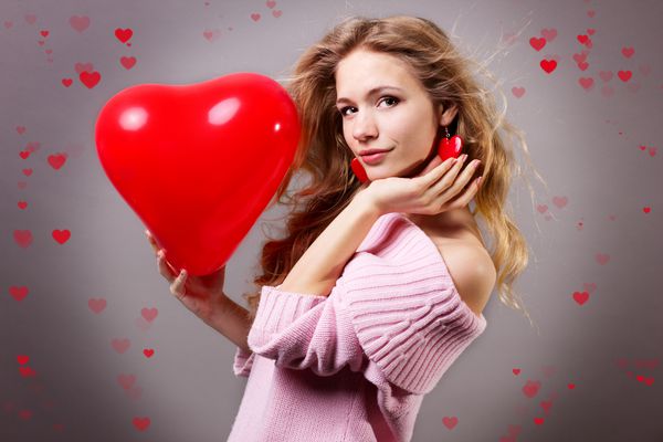 زن روز ولنتاین که بالن قلب قرمز را نگه می دارد