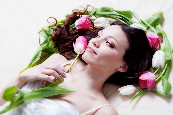 دختر زیبایی که با گل لاله ها در رختخواب است