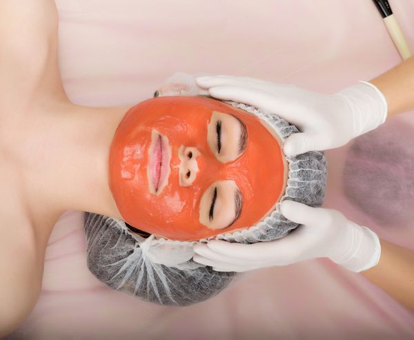 متخصص زیبایی ماسک زیبایی را بر روی صورت بیمار مشاوره حرفه ای انجام می دهد