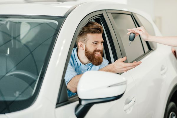 فروشنده با دادن کلید مرد و ریش جوانی که در ماشین جدیدی نشسته است