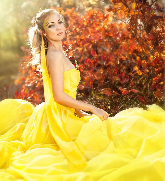 دختر زیبا جوان با لباس زرد در جنگل