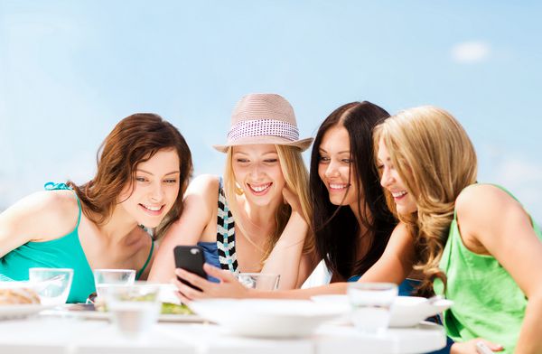 دخترانی که در کافه ساحل به تلفن هوشمند نگاه می کنند