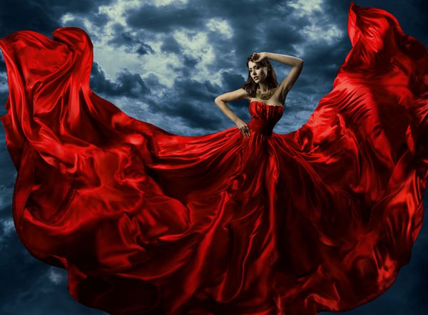 زن در لباس شب قرمز با لباس پارچه ای بلند پرواز می کند