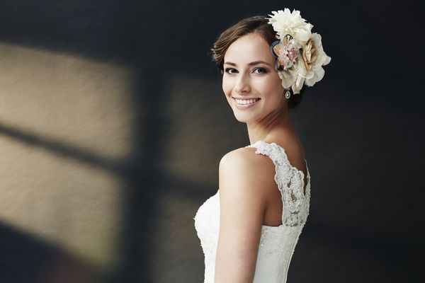عروس جوان پر زرق و برق در لباس عروسی لبخند زد