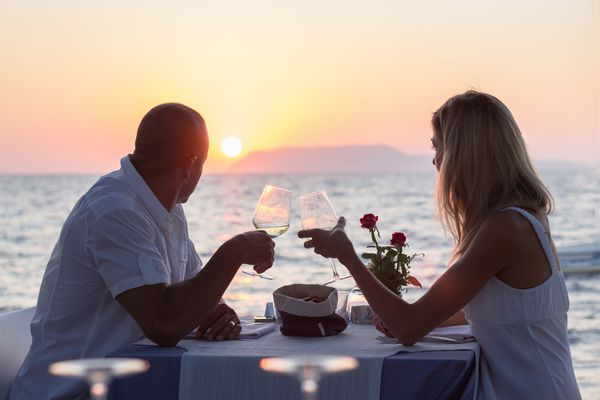 زن و شوهر در تاریخ عاشقانه در رستوران ساحل در غروب آفتاب