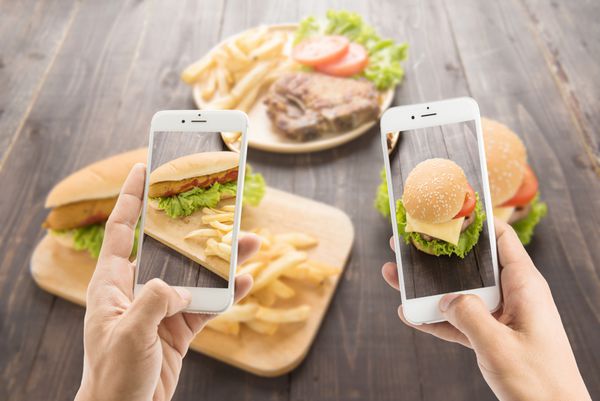 دوستان با استفاده از تلفن های هوشمند برای گرفتن عکس از هات داگ و همبرگر