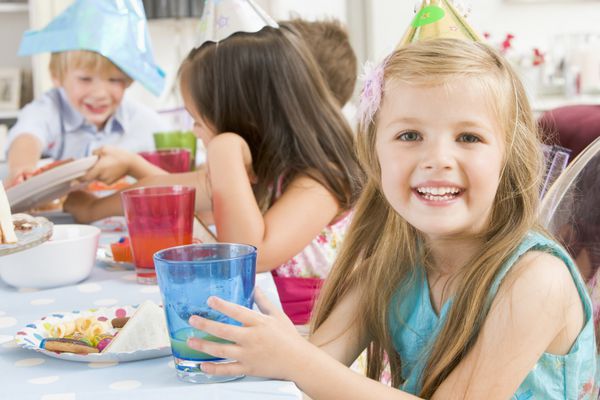 دختر جوان در مهمانی که در میز نشسته با لبخند غذا