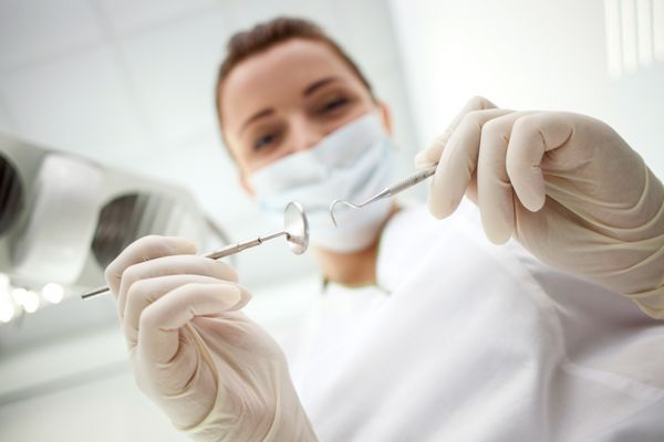 دندانپزشک زن حرفه ای در حال معالجه بیمار خود است