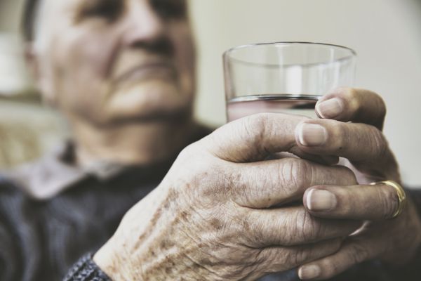 Seniorin mit einem glas wasser washer in hand