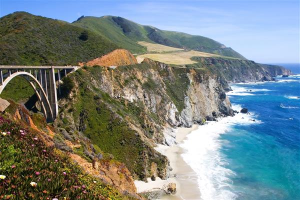 پل در منطقه در ساحل کالیفرنیا با آبهای فیروزه ای در ساحل سقوط می کند