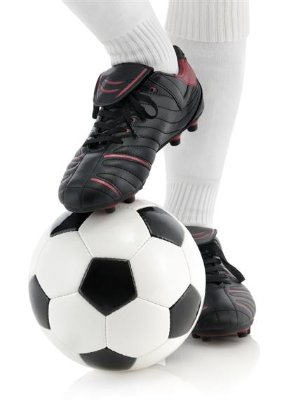 بازیکن فوتبال با کفش های براق و مشکی توپ را در زیر شوت استودیویی جدا از پای خود نگه می دارد