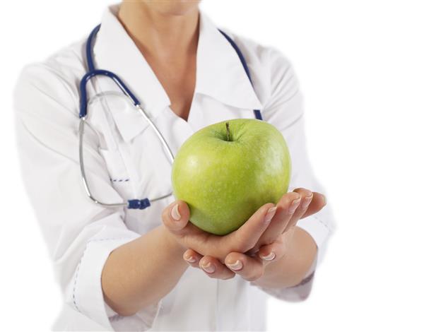 پزشک زنی که سیب سبز را در دست دارد و فضای کپی آن روی رنگ آبی است