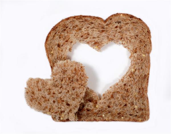 یک تکه نان گندم کامل با شکل قلب از مرکز بریده شده است