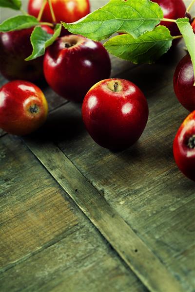 سیب قرمز با برگ روی میز چوبی با فضای کپی