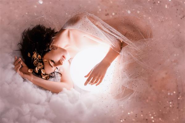 تصویر ملایم از خوابیدن فرشته در ماه در ابرهای صورتی روشن بدن برهنه دختر لاغر خوابیده در غبار پوشیده شده با پولک زرق و برق دار شاهزاده خانم شب با موهای تیره و یک تاج گل عالی