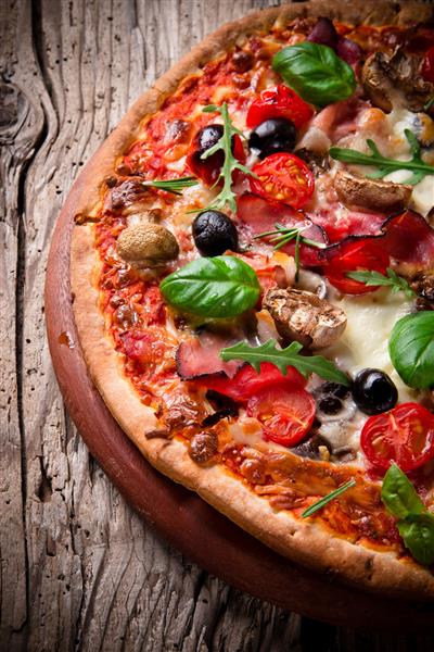 پیتزای خوشمزه ایتالیایی که روی میز چوبی سرو می شود