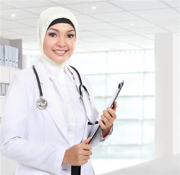 پرتره از یک زن مسلمان آسیایی مسلمان که در بیمارستان گیره کاغذ در دست دارد