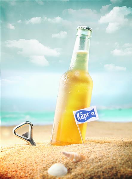 عکس زیبا از یک آبجو خنک و درب بازکن بطری در ساحل با برچسب