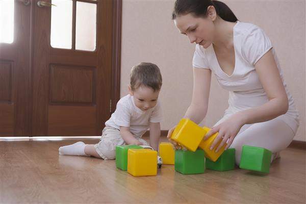 طول کامل مادر و پسر در خانه با مکعب های سبز و زرد بازی می کنند
