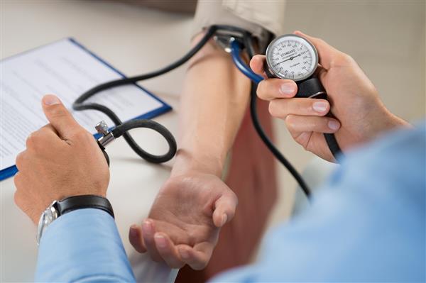 نزدیک شدن به پزشک در حال بررسی فشار خون بیمار