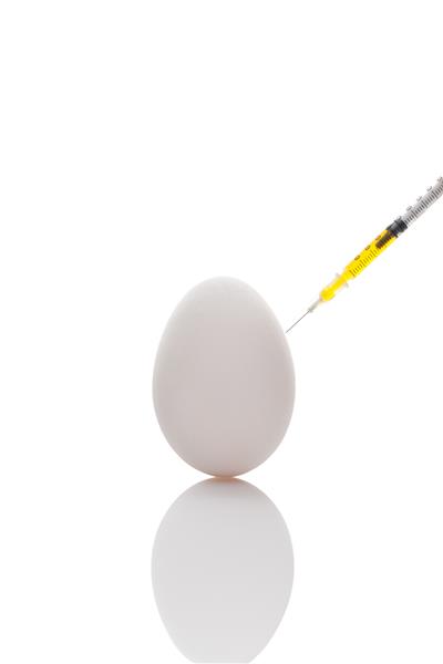 تزریق سرنگ زرد تخم مرغ سفید روی سطح بازتابنده
