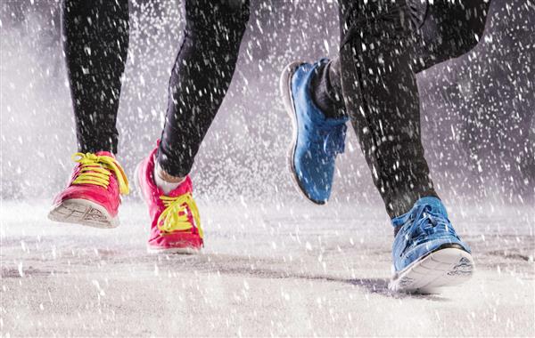 زن و مرد ورزشکار در حین تمرین زمستانی در هوای سرد برف در حال دویدن هستند
