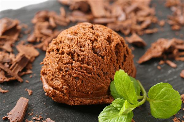 یک قاشق بستنی شکلاتی تلخ که روی یک بشقاب سیاه سرو می شود