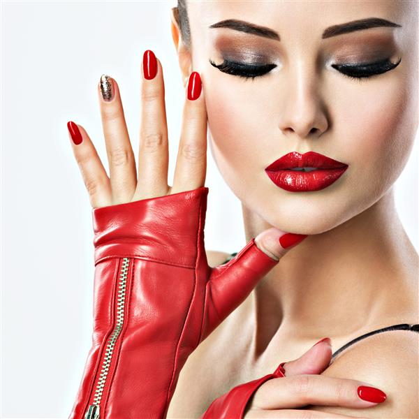 زن زیبا با ناخن های قرمز و آرایش مدل مد با مدل موهای خلاق شیک یک دختر جوان و بزرگسال کاملاً احساساتی با دستکش های چرمی قرمز