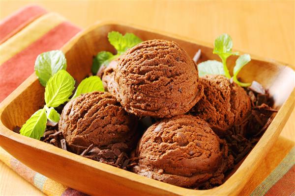 قاشق بستنی شکلاتی با پوسته شکلات که در یک کاسه چوبی سرو می شود