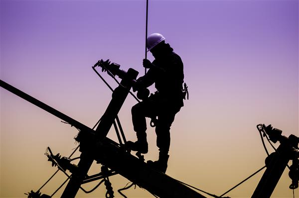 کارگر تعمیرکار خطوط برق در کار کوهنوردی در تیر برق