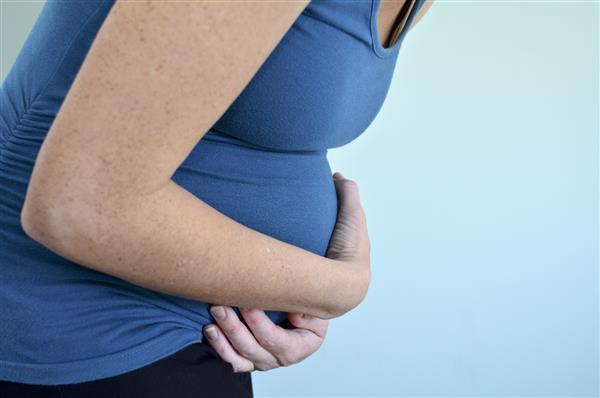 زن باردار مبتلا به معده درد شکم خود را از درد نگه می دارد عکس مفهومی از بارداری سبک زندگی زن باردار و مراقبت های بهداشتی
