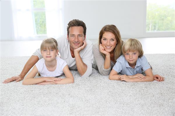 خانواده چهار نفره خوشبختی که در خانه روی فرش گذاشته اند