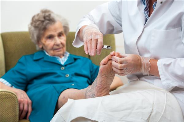 پرستار به یک زن مسن با کایروپدی و مراقبت از بدن در خانه کمک می کند